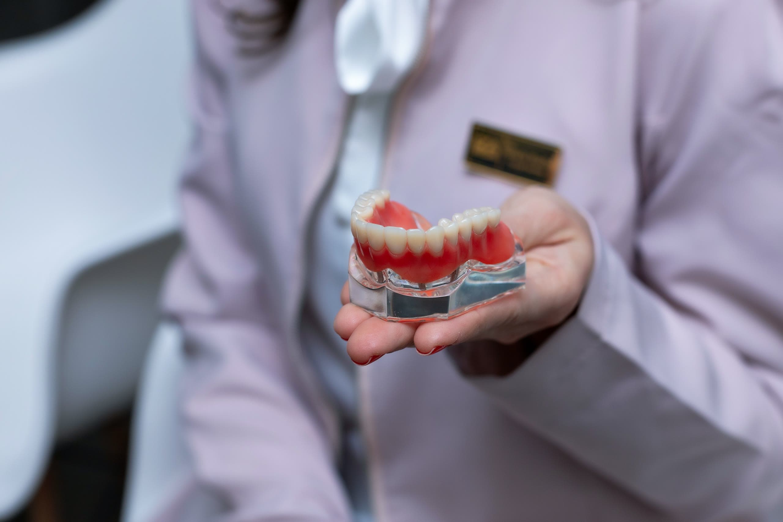 Modello di protesi totale sostenuta da impianti tenuto in mano da un'odontoiatra