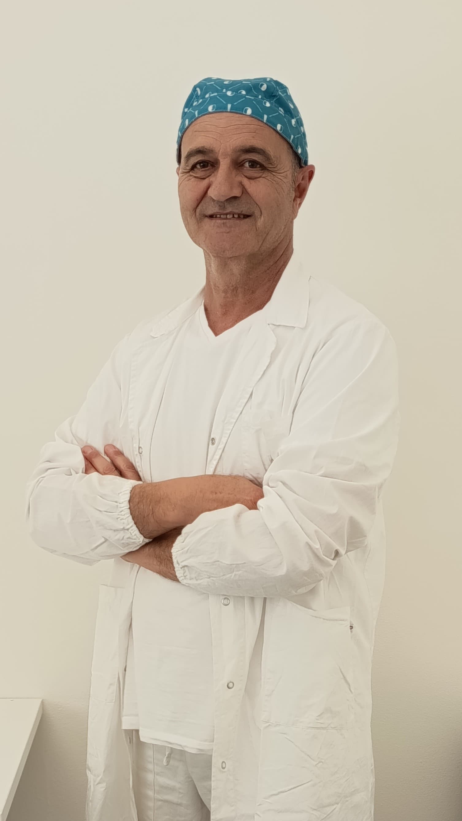 Il Dott. Gianni Monticelli in camice bianco e cuffia chirurgica, braccia conserte